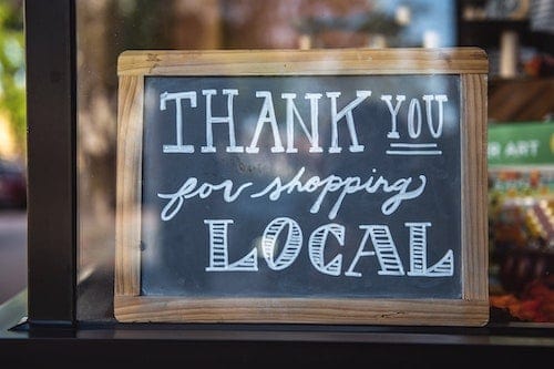 A chalkboard sign with a wooden frame reads, "THANK YOU for shopping LOCAL," displayed in a shop window—reminding customers that supporting local shops is as vital as effective SEO strategies for small businesses. - Clio Websites | Top Canadian Web Design Company