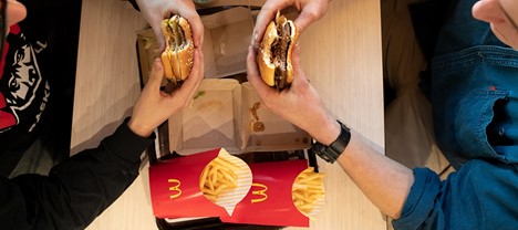 Two people sit at a table holding McDonald's burgers, with two red containers of fries on the tray—showing how great images like this can increase your website conversion rate. - Clio Websites | Top Canadian Web Design Company