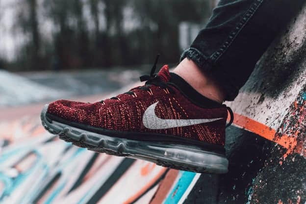 A person wearing a red and black Nike sneaker with a white swoosh logo stands on a colorful, graffiti-covered surface—showing how dynamic visuals can increase your website conversion rate using images. - Clio Websites | Top Canadian Web Design Company