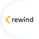 The image shows the word "rewind" in lowercase black letters, with a yellow, curved arrow-like shape pointing left before the text on a white circular background—a template trusted by many for its clean and modern design. - Clio Websites | Top Canadian Web Design Company