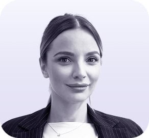 A woman with long, straight hair pulled back, wearing a pinstripe blazer and a necklace, smiles slightly at the camera against a light purple background—perfect for a profile on about clio websites. - Clio Websites | Top Canadian Web Design Company