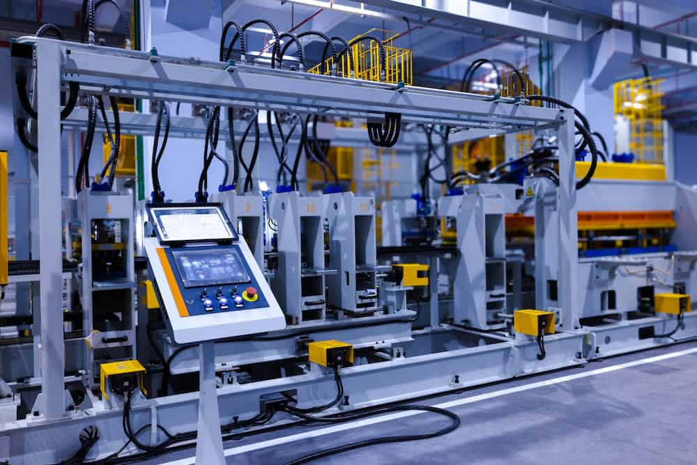 A modern automated factory line with industrial machines, control panels, and cables, featuring a digital touchscreen interface inspired by manufacturing web design and various mechanical components in a well-lit manufacturing facility. - Clio Websites | Top Canadian Web Design Company