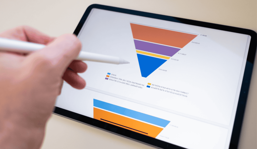 A hand holding a stylus points at a digital tablet displaying a colorful marketing funnel template and bar graph, with labeled segments and a legend, on a light background. - Clio Websites | Top Canadian Web Design Company