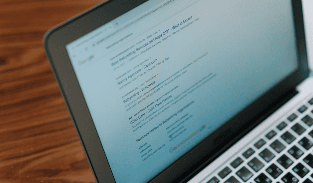 A laptop displays a Google search results page for "banking," showing links and snippets of information. The screen is at an angle, with part of the keyboard visible on a wooden surface—ideal for local SEO for Calgary small business research. - Clio Websites | Top Canadian Web Design Company